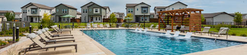 A swimming pool surrounded by lounge chairs and a wooden pergola.
