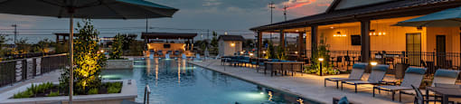 A poolside area with a table, chairs, and an umbrella.