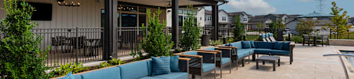 A patio area with a blue couch and a wooden table.