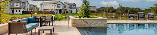 A pool with a bench and a table in front of a house.