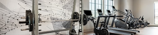 A gym with a row of treadmills and a row of weight machines.