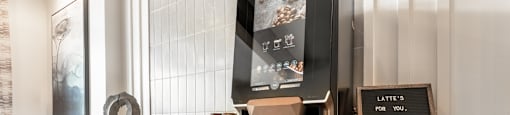 A coffee machine is on a counter with a sign that says "Latte's for you. For our furry friends.".