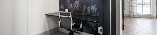 A black and white photo of a snowy landscape is on the wall above a desk with a white chair.