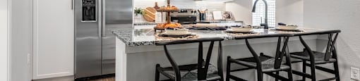 A kitchen with a refrigerator, microwave, and a table with chairs.