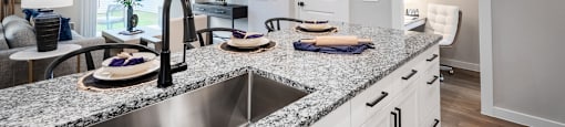 A modern kitchen with a granite countertop and stainless steel sink.