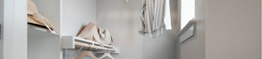 A walk-in closet with a carpeted floor and white shelves.
