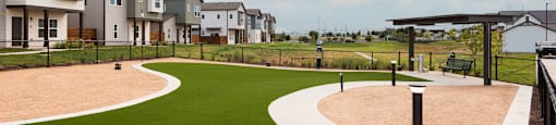 A park with a walking path and a grassy area in front of a row of houses.