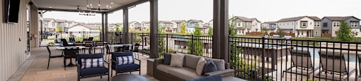 A patio with a table and chairs overlooking a pool.