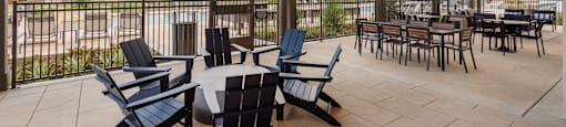 A patio with a table and chairs overlooking a fence and houses.