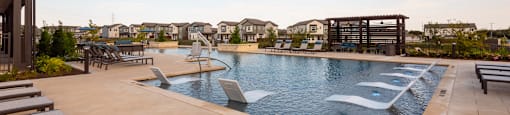 A large outdoor swimming pool with a slide and sun loungers.
