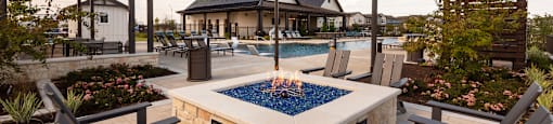 A patio with a fire pit and chairs.