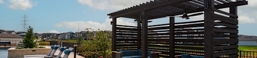 A wooden pergola with a bench and a table is on a patio.