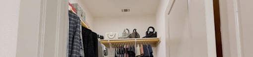 a walk in closet with clothes hanging on a rack and a door
