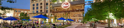 an evening view of a city street with people eating and drinking outside of a building