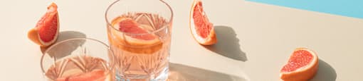 Two glasses of grapefruit juice on a table.