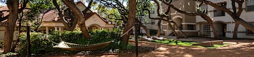 a hammock in the shade of trees in front of a building  at Hayden on West Ave, San Antonio, TX, 78216