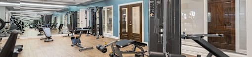 a gym with cardio equipment and weights on a wooden floor  at Hayden on West Ave, Texas