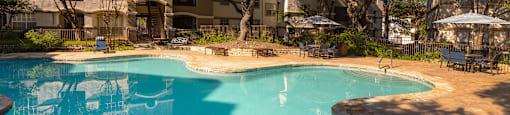 a swimming pool with trees and a building in the background  at Hayden on West Ave, San Antonio, Texas