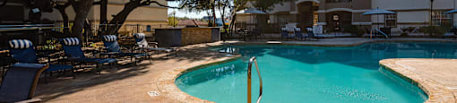 a swimming pool with chairs and an umbrella in front of an apartment building  at Hayden on West Ave, San Antonio, TX, 78216