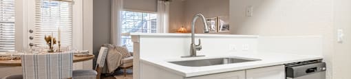 a kitchen with a sink and a dishwasher and a dining room with a table  at Hayden on West Ave, San Antonio, TX, 78216