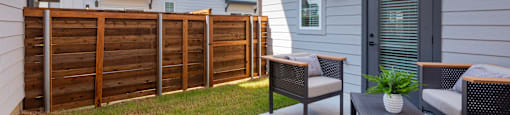 A patio with a table and chairs is in front of a house.