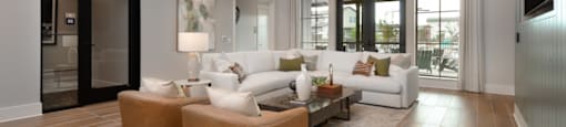 A modern living room with a white sofa and wooden floors.