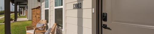 A house numbered 13003 has a porch with two chairs.