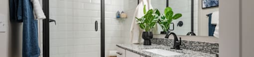 A bathroom with a white tiled shower and a marble countertop.