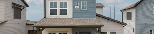 A house with a grey front yard and a grey garage door.