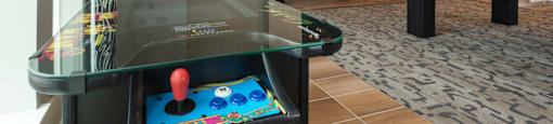 A small arcade table with a red ball on it sits in a room with a TV and a couch.