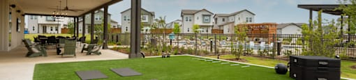 A covered patio area with a green lawn and a black trash bin.