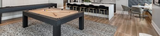 A room with a pool table and a bar area.