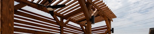 A wooden pergola with a bench and a table under it.
