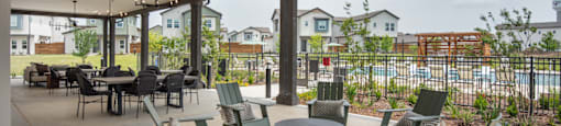 A patio with chairs and a table is covered by a roof.