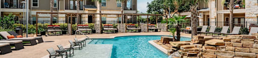 a swimming pool with chairs and buildings in the background