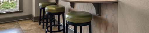 a bar with four stools and a mirror on the wall