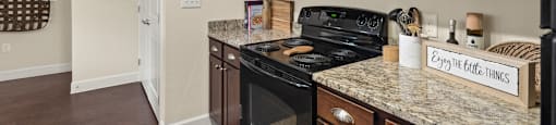 a kitchen with black appliances and granite counter tops and wooden cabinets