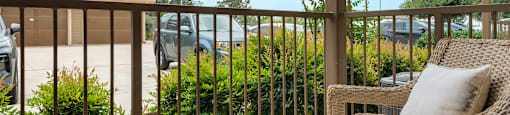 a porch with a wicker chair and a view of a parking lot
