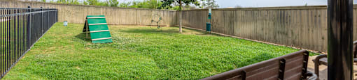 a backyard with a grass lawn and a fence and a bench