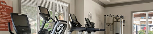 a gym with cardio equipment and a lot of windows