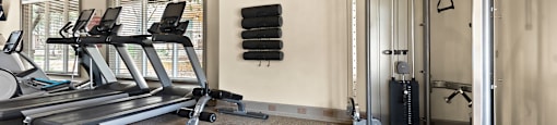 a gym with treadmills and weights in the corner of a room