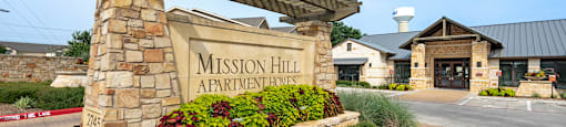 the entrance to mission hill apartments with a stone welcome sign