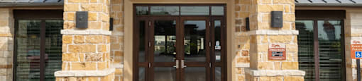 the front entrance of a building with a stone facade and wooden doors