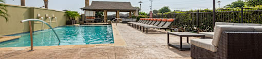 a swimming pool with lounge chairs and a gazebo on a sunny day