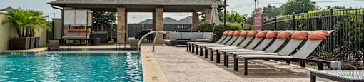 a pool with chairs and a gazebo on the side of a house