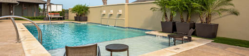 a swimming pool with chairs and palm trees in front of a house