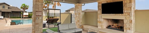 the estates outdoor living area with fireplace and tv