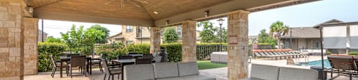a covered patio with couches and tables and a pool