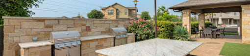 a patio with an outdoor kitchen and a stone wall