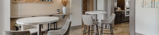 a dining area with tables and chairs and a kitchen in the background